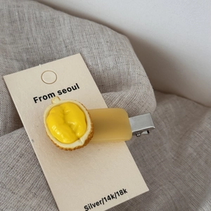 Detail of creative yellow acetate hair clip featuring realistic durian fruit design