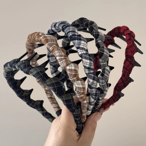 Detail of plaid fabric headband featuring a non-slip comb teeth design and twisted texture