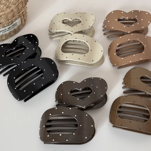Close-up of polka dot heart and oval shaped hair clips in various elegant colors