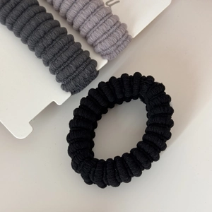 Detailed macro of three high-elasticity seamless hair ties in black and grey tones