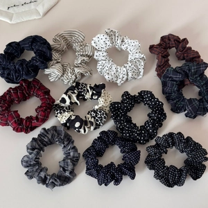 Flat lay of eleven colorful polka dot and plaid pleated scrunchies on a beige background
