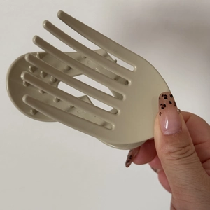 Close-up of beige matte polka dot oval hair claw clip with multi-tooth design detail