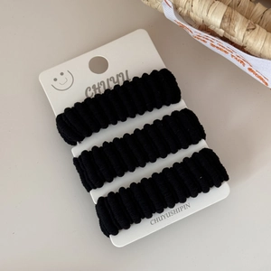 Detailed view of three black elastic hair ties on display card for stylish hair styling