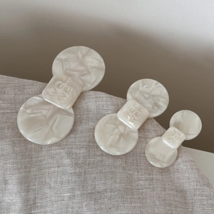 Macro detail of acetate bow hair clips in cream beige marble texture and three sizes