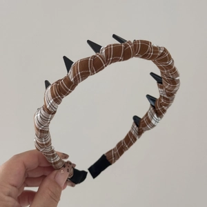 Detail of plaid fabric headband with black punk spikes and protective end tips