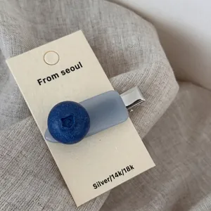 Close-up of a blueberry acetate hair clip with matte base on a fabric background