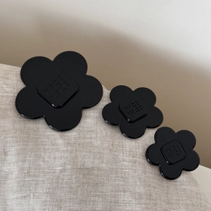 Detailed view of glossy black floral hair clips with embossed lettering in three sizes