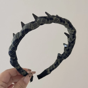 Close-up of blue-grey plaid fabric headband with black punk-style metal conical spikes