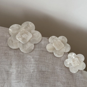 Detailed macro shot of acetic acid flower hair clips with marble texture and letter engraving