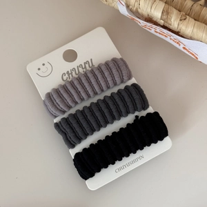 Detailed macro view of three high-elasticity wide ribbed hair ties in grey and black set