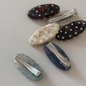 Detailed view of oval rhinestone hair clips with tortoise shell and marble textures