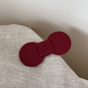 Detailed macro view of the deep burgundy acetate hair clip with embossed brand logo