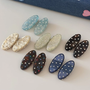 Macro detail of oval resin hair clips with sparkling rhinestones in assorted colors