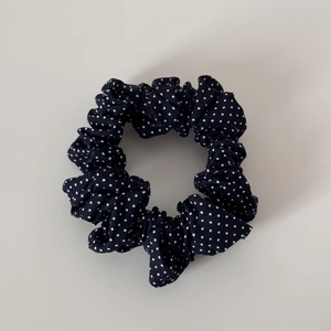 Detailed view of the navy blue polka dot scrunchie fabric texture and pleated finish