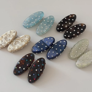 Detail view of oval rhinestone hair clips in various patterns like marble and tortoiseshell