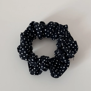 Macro shot of black and white polka dot pattern on pleated cotton scrunchie hair tie
