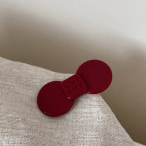 Detailed macro view of red acetate bow hair clip with letter engraving on linen fabric