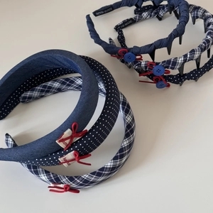Dettaglio di cerchietti a scacchi blu navy con fiocchi rossi e bottoni decorativi