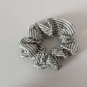 Detail shot of white scrunchie with black horizontal stripes and elastic cotton texture