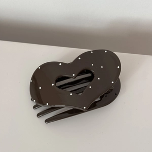 Detail view of heart-shaped dark brown hair claw clip with white polka dots