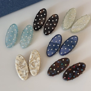 Detailed view of oval acetate hair clips with sparkling rhinestones in assorted colors