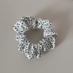 Detailed view of the retro black polka dot scrunchie with soft pleated fabric texture