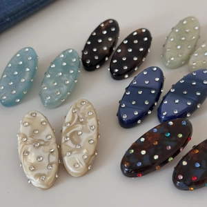 Macro shot of oval resin hair clips with rhinestones in marble and tortoiseshell patterns