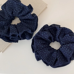 Detail view of two large navy blue fabric scrunchies with light blue polka dot pattern