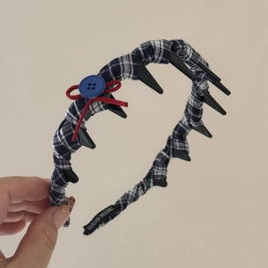 Dettaglio dei denti interni del cerchietto a quadri blu con fiocco rosso e bottone blu