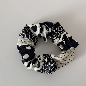 Close-up of black and white polka dot pleated fabric scrunchie with elastic band texture