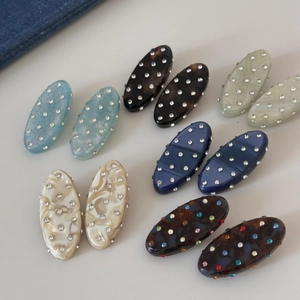 Detail view of oval resin hair clips with sparkling rhinestones in various marble patterns