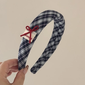 Dettaglio del cerchietto scozzese blu navy con fiocco rosso ed etichetta fatta a mano