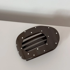 Polka dot pattern on a glossy dark brown hair claw clip with a wide rounded design