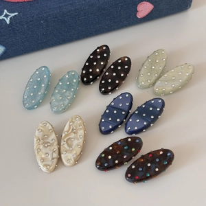 Detail of oval rhinestone hair clips in various colors like marble and tortoise shell