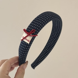 Dettaglio del cerchietto blu navy a pois con fiocco rosso ed etichetta fatta a mano