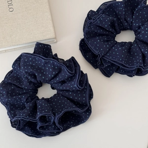 Navy blue fabric scrunchies with light blue polka dots set on a clean white surface