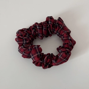 Detail of red Scottish plaid fabric scrunchie with elastic band and dense pleats