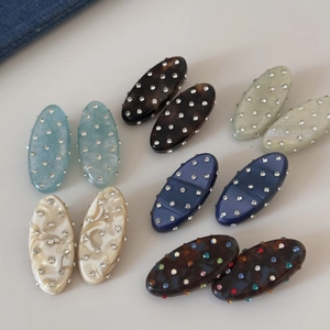 Detail view showing six pairs of oval rhinestone hair clips with marble patterns