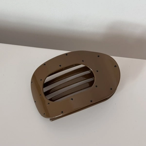 Close-up of brown polka dot oval hair claw clip with internal teeth for secure styling