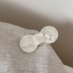 Detail of cream marble acetate hair clip featuring engraved text on textured fabric