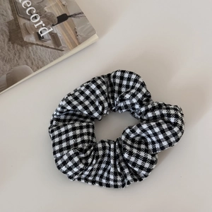 Dettaglio del grande elastico per capelli con motivo pied de poule bianco e nero retrò
