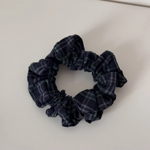 Detail view of small blue and green plaid scrunchie with soft pleated fabric texture