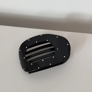 Detail view of oval polka dot hair clip made of premium glossy acetate material