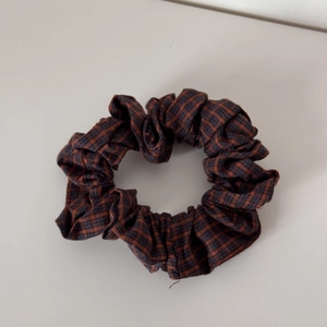 Close-up detail of retro plaid pleated scrunchie in deep orange and navy blue cotton fabric