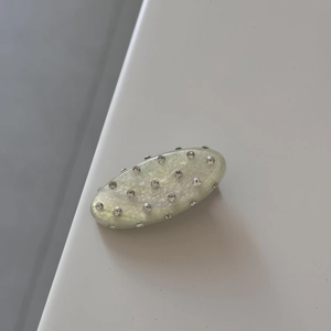 Close-up of oval hair clip with sparkling rhinestones and pearlescent cream finish