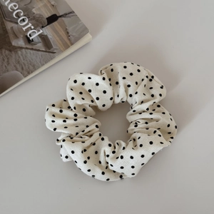 Dettaglio dell'elastico per capelli in tessuto a pois crema con morbide pieghe elastiche