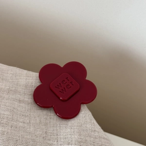 Detailed macro shot of a dark red acetate flower hair clip featuring wer wer engraved logo