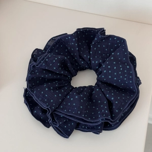 Detail of navy blue fabric scrunchie with light blue polka dots and pleated texture