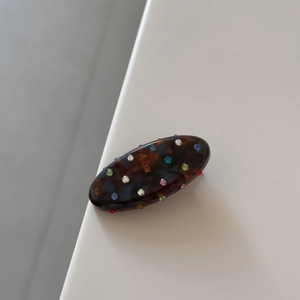 Close-up of vintage oval hair clip with tortoiseshell pattern and colorful rhinestones