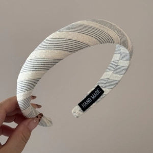 Detailed close-up of blue and white striped fabric headband with Hand Made label